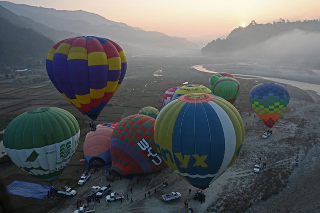 Hot air balloons prepare to rise in the sky during the international hot-air balloon festival in Pokhara on January 1, 2025. With Nepal's snowy Himalayan peaks as a backdrop, the sky above Pokhara transformed into a vibrant canvas of colours for the country's first hot-air balloon festival. (Photo by Prakash Mathema/AFP Photo)