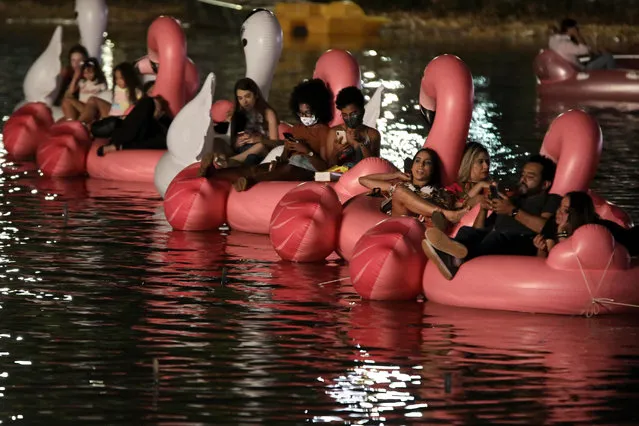 People lounge on Inflatable unicorns and flamingos on Sarah Kubstichek Lake as they watch a movie during the first Floating Festival in Brasilia, Brazil, Wednesday, September 30, 2020. The festival is the first in Brazil were people sit in inflatable boats and pedal boats, anchored in fixed spots and watch a movie, like an aquatic version of a drive-in cinema. (Photo by Eraldo Peres/AP Photo)