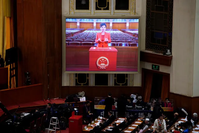 A guide explains the voting procedure is seen on a giant screen before the third plenary session of the National People's Congress (NPC), where delegates will vote on a constitutional amendment lifting presidential term limits, at the Great Hall of the People in Beijing, China March 11, 2018. (Photo by Jason Lee/Reuters)