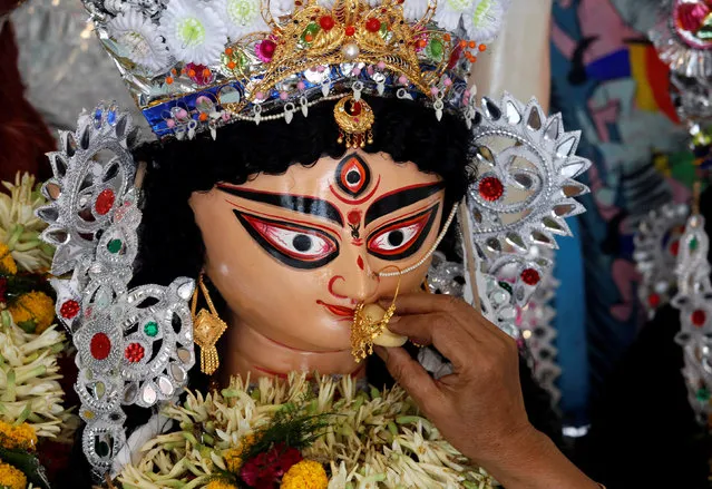 A devotee offers sweets to the idol of the Hindu goddess Durga while offering prayers on the last day of the Durga Puja festival in Kolkata, India October 11, 2016. (Photo by Rupak De Chowdhuri/Reuters)