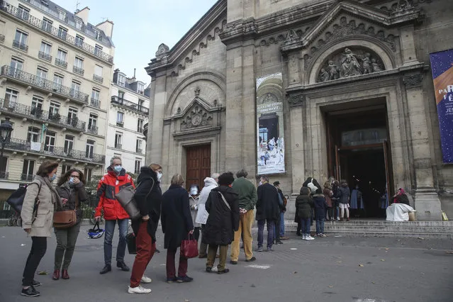 Church-goers wearing face masks as a precaution against the coronavirus lineup outside the Notre-Dame-des-Champs church in Paris, Sunday, November 29, 2020. French churches, mosques and synagogues can open their doors again to worshippers – but only a few of them, as France cautiously starts reopening after a second virus lockdown. Some churches may defy the 30-person limit they feel as too unreasonable, and other sites may stay closed until they can reopen for real. (Photo by Michel Euler/AP Photo)
