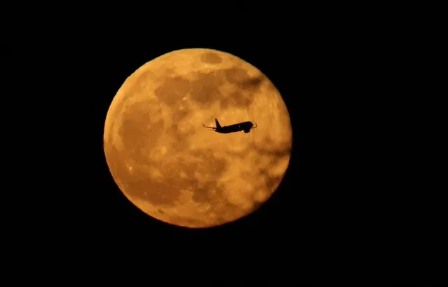 A plane passes in front of a full moon, known as the worm moon, in Manchester, Britain on March 7, 2023. (Photo by Phil Noble/Reuters)