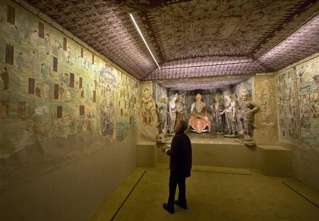 A woman views a full scale replica cave from the 8th century that contains the Bodhisattva of the Mogao Caves, in “Dunhuang: Buddhist Art at the Gateway of the Silk Road”, at the China Institute, in New York,  Tuesday, April 24, 2013. (Photo by Richard Drew/AP Photo)