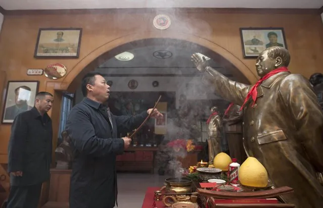 Tian Haiming, a sculptor, burns incense in front of a copper statue of China's late Chairman Mao Zedong before handing it to the buyer,  in Shaoshan, Hunan province, December 8, 2014. (Photo by Darwin Zhou/Reuters)