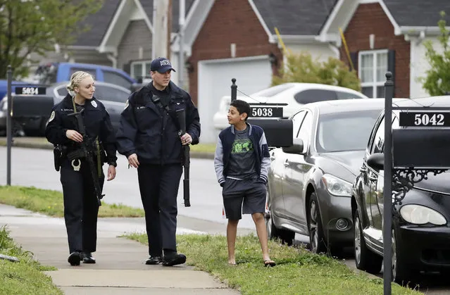 Nashville police officers talk to a boy as they search a neighborhood near a Waffle House restaurant Sunday, April 22, 2018, in Nashville, Tenn. At least four people died after a gunman opened fire at the restaurant early Sunday. (Photo by Mark Humphrey/AP Photo)