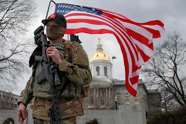 An armed protester stands in front of the Statehouse Sunday, January 17, 2021, in Concord, N.H. (Photo by Winslow Townson/AP Photo)