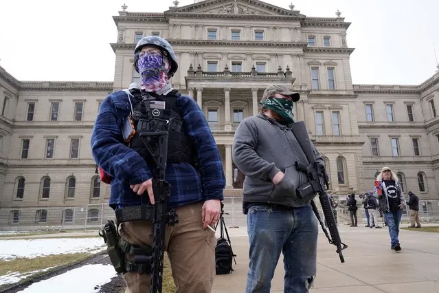 Two men with rifles stand outside the state Capitol in Lansing, Mich., Sunday, January 17, 2021. (Photo by Paul Sancya/AP Photo)