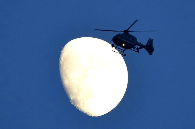 A helicopter flies in front of the moon at the airport in Berlin on June 19, 2013 ahead of the departure of US President Barack Obama. Obama said Russian and US nuclear weapons should be slashed by up to a third in a keynote speech in front of Berlin's iconic Brandenburg Gate in which he called for a world of “peace and justice”. (Photo by Odd Andersenodd Andersen/AFP Photo)