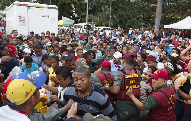 Venezuelan soldiers try to control the crowd as people attempt to buy chickens at a Mega-Mercal, a subsidized state-run street market, in Caracas January 24, 2015. (Photo by Carlos Garcia Rawlins/Reuters)