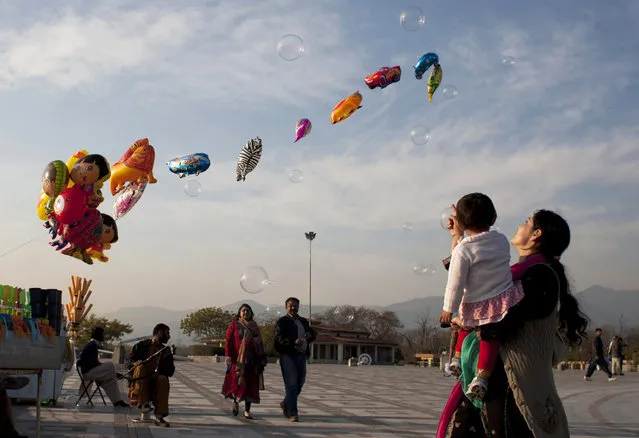 A Pakistani woman shows her daughter bubbles released by a vendor in Lake View park in Islamabad, Pakistan, Saturday, January 24, 2015. (Photo by Shakil Adil/AP Photo)