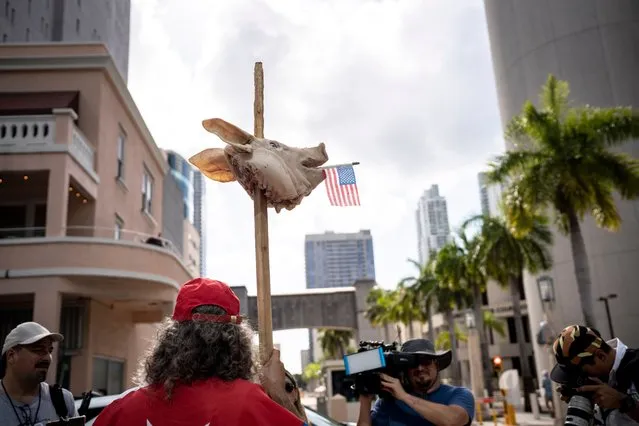 Osmany Estrada (out of frame) shows his support with a pig's head on a stake in front of the Wilkie D. Ferguson Jr. United States Courthouse before the arraignment of former President Donald Trump in Miami, Florida on June 13, 2023. Trump is appearing in court in Miami for an arraignment regarding 37 federal charges, including violations of the Espionage Act, making false statements, and conspiracy regarding his mishandling of classified material after leaving office. (Photo by Thomas Simonetti for The Washington Post)