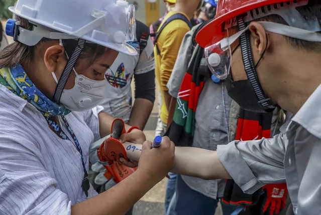 An anti-coup protester writes vital emergency information of another protester on his arm in Yangon, Myanmar Wednesday, March 3, 2021. (Photo by AP Photo/Stringer)