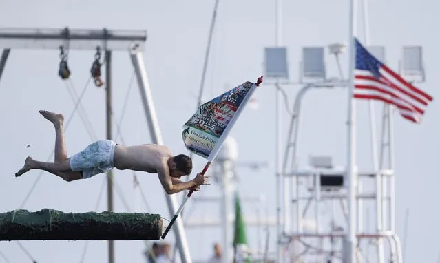Competitor Colin Sweet dives for the flag at the end of the 'Greasy Pole' as part of the sporting activities of the city wide celebrations of St. Peter's Fiesta in Gloucester, Massachusetts, USA on June 23, 2023. St. Peter's Fiesta is an annual celebration, taking place on the weekend closest to the Feast Day of St. Peter, 29 June and is sponsored by the Italian-American fishing community of Gloucester. (Photo by C.J. Gunther/EPA/EFE)