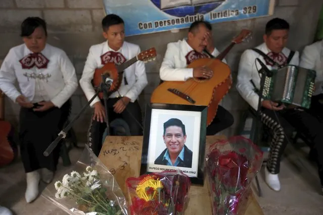 A framed portrait of Elfego Miranda Diaz, one of Guatemalan migrants who was killed near the U.S.-Mexico border in January, sits on top of the coffin that contains his remains during a wake in his home in Comitancillo, Guatemala, Saturday, March 13, 2021. Thousands of residents of this Guatemalan town turned out Friday night amid tears and applause to receive the remains of 16 of their own, found piled in a charred pickup truck in Camargo, across the Rio Grande from Texas. (Photo by Moises Castillo/AP Photo)