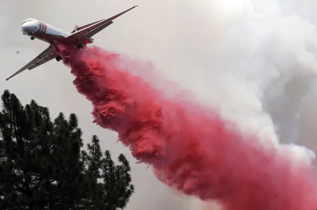 An air tanker drops retardant onto a wildfire, Thursday, July 26, 2018, near Mountain Center, Calif. A fast-moving wildfire, believed to have been sparked by arson, tore through trees, burned homes and forced evacuation orders for an entire mountain town as California sweltered under a heat wave and battled ferocious fires at both ends of the state. (Photo by Marcio Jose Sanchez/AP Photo)