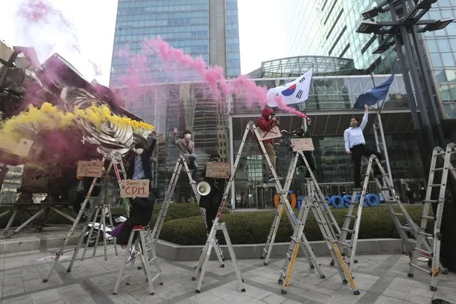 South Korean peace activists on the ladders light smoke bombs during a rally supporting Myanmar's democracy in Seoul, South Korea, Monday, February 22, 2021. (Photo by Ahn Young-joon/AP Photo)