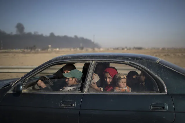 An Iraqi family sits inside a car as they wait at a checkpoint near Qayara, south of Mosul, Iraq, Sunday, November 20, 2016. Iraqi troops on Sunday fortified their positions in Mosul neighborhoods retaken from the Islamic State group as their advance toward the city center was slowed by sniper fire and suicide bombings, as well as concern over the safety of civilians. (Photo by Felipe Dana/AP Photo)