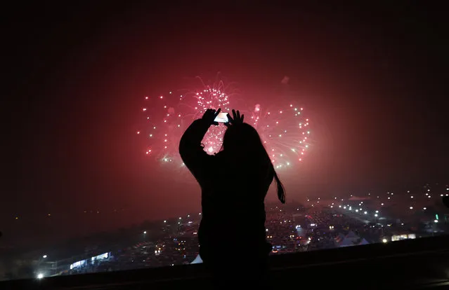 A woman uses her smartphone to take picture of fireworks while celebrating the New Year at the Imjingak Pavilion near the border village of Panmunjom in Paju, South Korea, Friday, January 1, 2016. (Photo by Lee Jin-man/AP Photo)