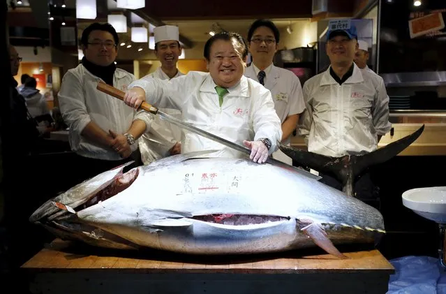 Kiyomura Co's President Kiyoshi Kimura (C), who runs a chain of sushi restaurants, holds a sword as he poses with a 200 kg (400 lbs) bluefin tuna at his sushi restaurant outside Tsukiji fish market in Tokyo, Japan, January 5, 2016. Kimura won the bid for the tuna caught off Oma, Aomori prefecture, northern Japan, with a 14 million yen (117,000 USD) at the fish market's first tuna auction this year. (Photo by Toru Hanai/Reuters)