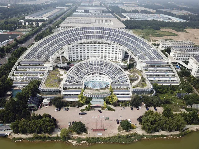 In this Thursday, August 2, 2018, aerial photo, the Micro-E Hotel's massive array of solar panels are spread over its property in Dezhou in the eastern Shandong province in China. The city of Dezhou began a drive to become a solar energy hub in China in 2005 and has since successfully courted national investment and backing. China is the world's biggest consumer and producer of solar technologies. (Photo by Sam McNeil/AP Photo)