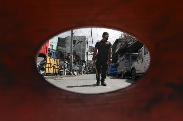 A policeman patrols inside a village that was placed under lockdown as the government implements stricter measures to prevent the spread of the coronavirus in Manila, Philippines on Monday, March 22, 2021. The Department of Health reported over 8,000 new COVID-19 cases Monday, the highest number since the pandemic hit the country last year as it struggles to contain an alarming surge in coronavirus infections. (Photo by Aaron Favila/AP Photo)