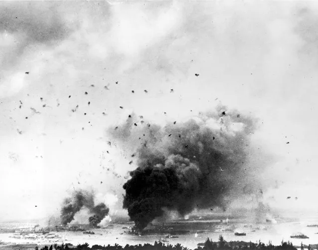 Flak bursts of anti-aircraft shells pepper the skyline above rising smoke from the battleship USS Arizona during the Japanese raid on Pearl Harbor, Hawaii, U.S. December 7, 1941. (Photo by Reuters/U.S. Navy/National Archives)