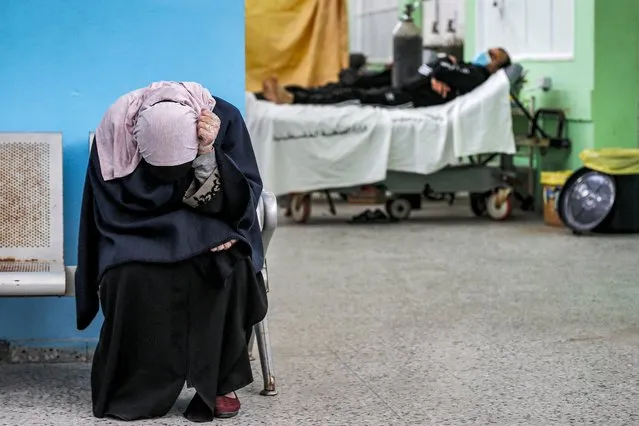 A Palestinian woman reacts while waiting for her husband (background) at the COVID-19 intensive care unit of al-Shifa Hospital in Gaza City on April 7, 2021. (Photo by Mahmud Hams/AFP Photo)