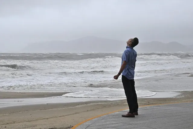 A man stands near a beach during winds brought on by Typhoon Khanun at the southeastern port city of Busan on August 10, 2023. (Photo by Anthony Wallace/AFP Photo)
