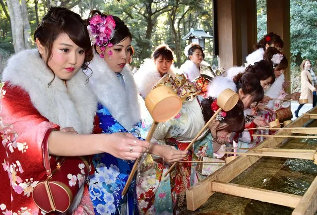 Twenty-year-old female tour guides dressed in traditional kimonos wash their mouths and hands at Tokyo's Meiji shrine before attending a purification ceremony with a Shinto priest to celebrate Japan's Coming-of-Age Day on January 8, 2016. Since tour guides will be busy working on Japan's national holiday Coming-of-Age Day on January 11, the company held a ceremony. Young people turning 20 are officially recognised as adults in Japan. (Photo by Yoshikazu Tsuno/AFP Photo)