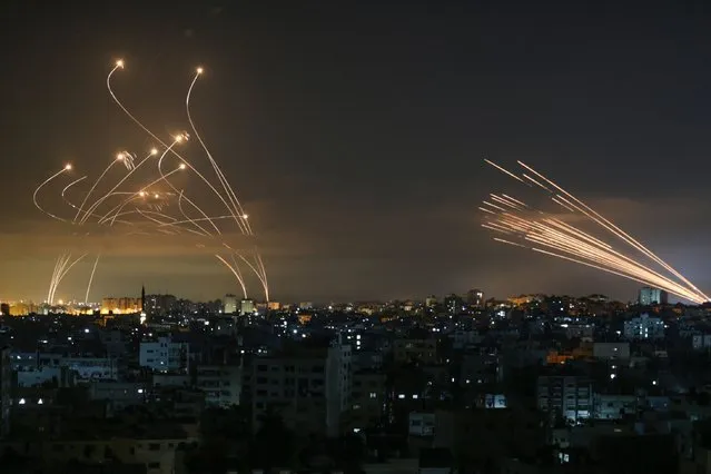 The Israeli Iron Dome missile defence system (L) intercepts rockets (R) fired by the Hamas movement towards southern Israel from Beit Lahia in the northern Gaza Strip as seen in the sky above the Gaza Strip overnight on May 14, 2021. Israel bombarded Gaza with artillery and air strikes on Friday, May 14, in response to a new barrage of rocket fire from the Hamas-run enclave, but stopped short of a ground offensive in the conflict that has now claimed more than 100 Palestinian lives As the violence intensified, Israel said it was carrying out an attack “in the Gaza Strip” although it later clarified there were no boots on the ground. (Photo by Anas Baba/AFP Photo)