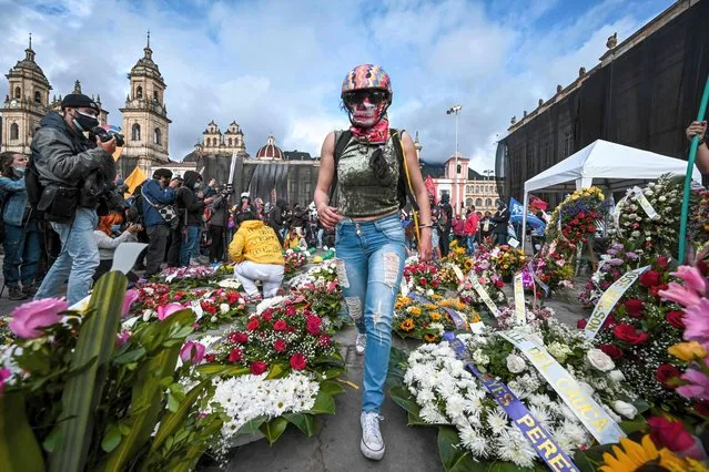 A woman walks amid wreaths in honour of people killed during protests against the government placed outside the Congress building during a session in which Colombian Defense Minister Diego Molano's censure motion is discussed, in Bogota on May 24, 2021. (Photo by Juan Barreto/AFP Photo)