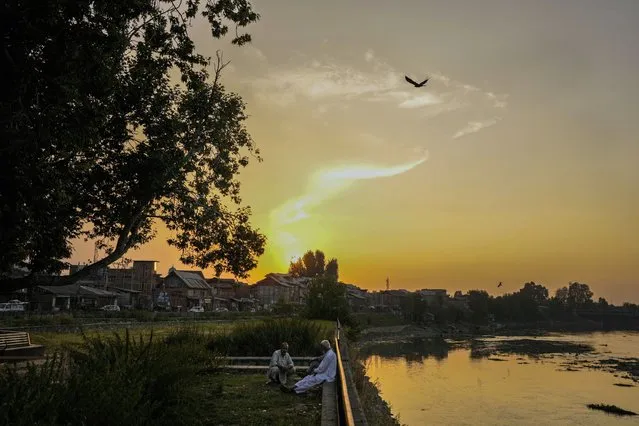 Men chat by the banks of the Jhelum river in Srinagar, Indian controlled Kashmir, Wednesday, September 13, 2023. (Photo by Mukhtar Khan/AP Photo)