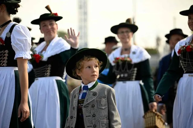 A young participant walks with women in traditional dresses during the costume parade at the Oktoberfest 2023, Munich's annual beer festival, on September 17, 2023 in Munich, southern Germany. The world biggest beer festival Oktoberfest will be open until October 3, 2023 at Munich's Theresienwiese fair grounds. (Photo by Tobias Schwarz/AFP Photo)