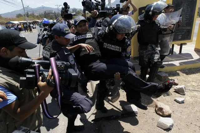 Policemen carry an injured colleague during a protest in Tegucigalpa March 25, 2015. (Photo by Jorge Cabrera/Reuters)