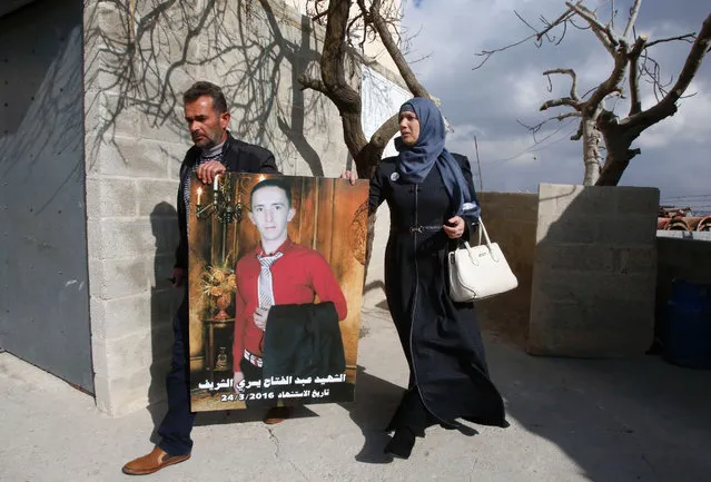 Rajaa and Yousri the mother and father of Abdul Fatah al-Sharif (portrait) head out into the streets in the West Bank town of Hebron on January 4, 2017, after watching on television the verdict of the trial of Israeli soldier Elor Azaria who killed their son. Elor Azaria who shot dead Sharif as he lay wounded on the ground posing no apparent threat was convicted of manslaughter after a trial that deeply divided the country. (Photo by Hazem Bader/AFP Photo)