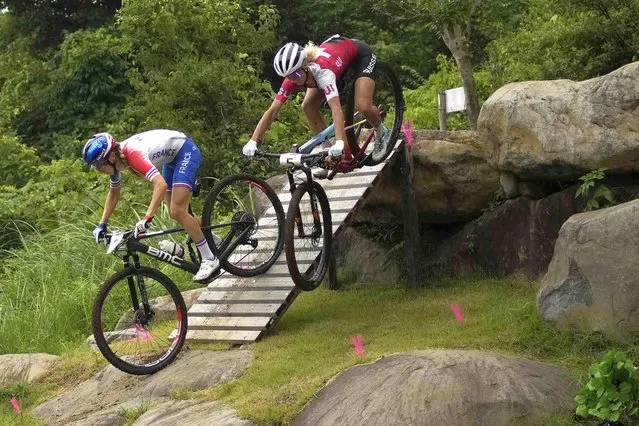 Jolanda Neff of Switzerland (5) flies off the ramp and nearly crashes as she competes against Pauline Ferrand Prevot of France during the women's cross-country mountain bike competition at the 2020 Summer Olympics, Tuesday, July 27, 2021, in Izu, Japan. (Photo by Christophe Ena/AP Photo)