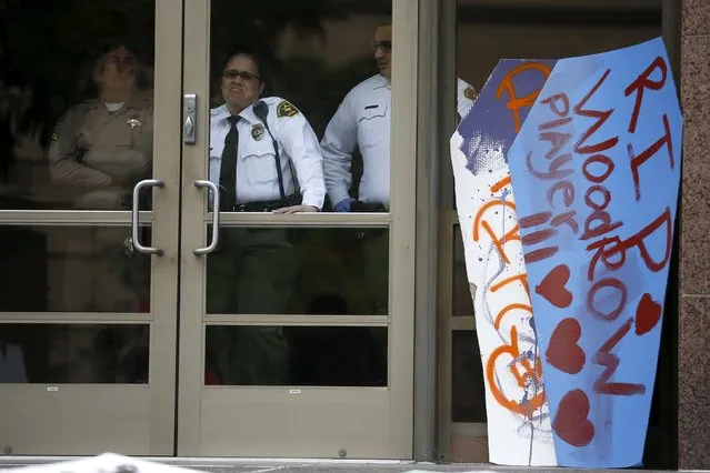 LA sheriff's deputies look out of the LA County Board of Supervisors' office where cardboard coffins were leant to commemorate the more than 617 people march organizers say have been killed by law enforcement in LA County since 2000, in Los Angeles, California April 7, 2015. (Photo by Lucy Nicholson/Reuters)