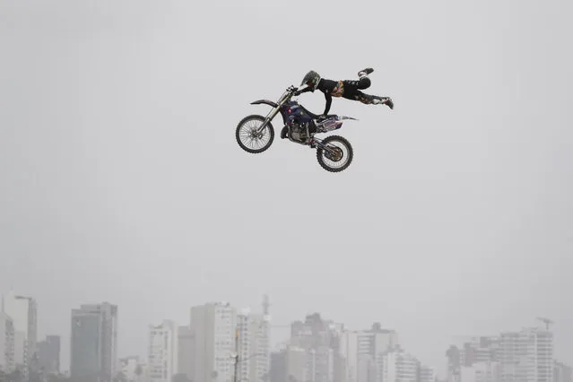 In this January 6, 2019 photo, a rider performs a stunt prior to the podium ceremony before the start of the Dakar Rally in Lima, Peru. The 41st edition of Dakar Rally starts in Lima on Jan. 7, after today's symbolic start ceremony. (Photo by Martin Mejia/AP Photo)