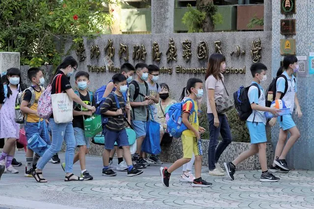 Elementary school students wear face masks to protect against the spread of the coronavirus and walk into the school gate in Taipei, Taiwan, Wednesday, September 1, 2021. Schools across Taiwan reopened for the academic year Wednesday, after they shut down in the face of the island’s largest COVID-19 outbreak in May. (Photo by Chiang Ying-ying/AP Photo)