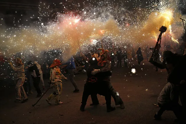 In this photo taken on Monday, January 16, 2017, revelers dressed as demons called “Dimonis” hold fireworks as they take part in a “Correfoc” or 'run with fire' party during traditional celebrations in honor of Saint Anthony in Muro village in the Mediterranean island of Mallorca, Spain. Mixing pagan and religious traditions from medieval times, the fire and demon festivals are held in towns across the island of Mallorca each Jan. 16-17 to celebrate the day of Saint Anthony the Abbot, the patron saint of animals. (Photo by Francisco Seco/AP Photo)