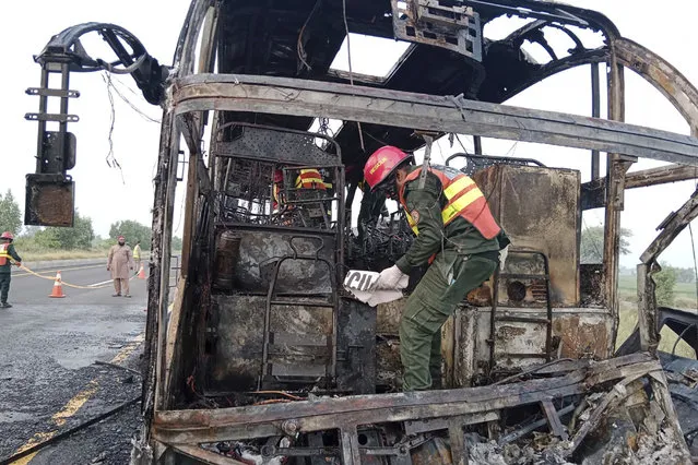 In this photo released by the Rescue 1122 Emergency Department, rescue workers examine a burnt bus at the accident site on a highway in Pindi Bhattian, Pakistan, Sunday, August 20, 2023. A bus in Pakistan caught fire after hitting a van parked on the shoulder of an intercity highway in eastern Punjab province, killing multiple people and injuring others, police and rescue officials said Sunday. (Photo by Rescue 1122 Emergency Department vis AP Photo)