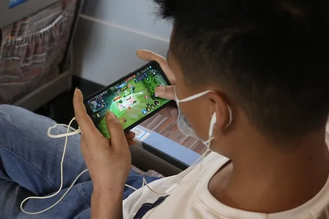 A man plays the popular Honor of Kings online game from Chinese gaming platform Tencent during a high speed train from Henan to Beijing Wednesday, September 15, 2021. China has set new rules limiting the amount of time kids can spend playing online games. (Photo by Ng Han Guan/AP Photo)