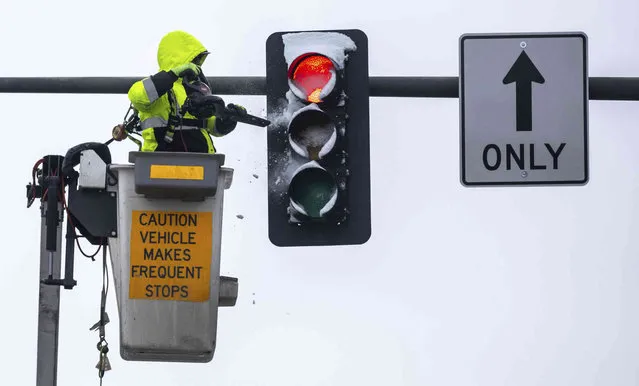 A worker uses a leaf blower to clear snow off a stoplight at 10th and Farnam Streets in downtown Omaha, Neb., Wednesday, January 10, 2024. A winter storm left several inches in the area. (Photo by Chris Machian/Omaha World-Herald via AP Photo)