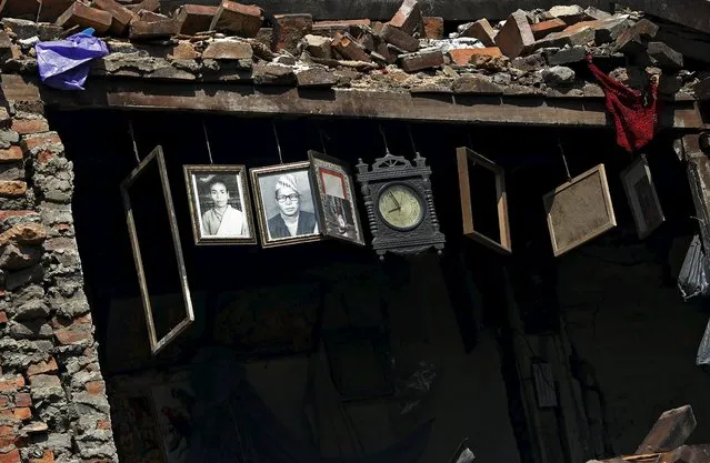 Framed photographs and a clock are seen hanging inside a damaged house after Saturday's earthquake in Bhaktapur, Nepal April 27, 2015. (Photo by Adnan Abidi/Reuters)