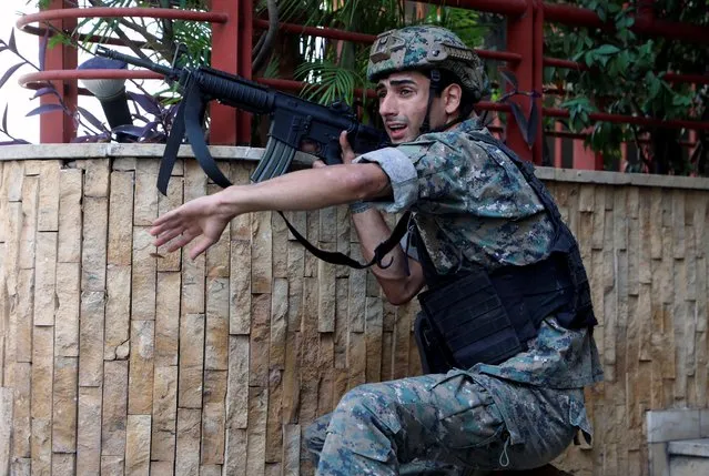An army soldier gestures after gunfire erupted at a site near a protest that was getting underway against Judge Tarek Bitar who is investigating last year's port explosion, in Beirut, Lebanon on October 14, 2021. (Photo by Mohamed Azakir/Reuters)