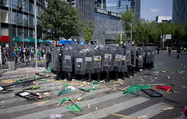 In this Wednesday, February 1, 2017 photo, riot police take cover behind their shields during a clash with farm workers in Mexico City. Rural residents from across the country flooded major boulevards of the capital Tuesday, as they denounced a gasoline price hike that has raised the price of tractor fuel and called for the renegotiation of NAFTA to make it more favorable to small farmers. (Photo by Eduardo Verdugo/AP Photo)