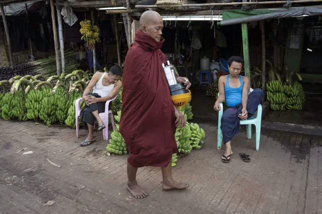 A Myanmar Buddhist monk walks to collect morning alms as vendors selling bunches of banana wait for customers near a jetty Tuesday, March 15, 2016, in Yangon, Myanmar. (Photo by Hkun Lat/AP Photo)