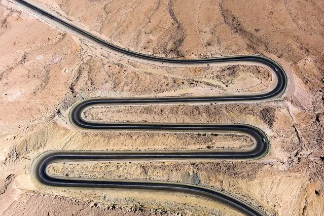 Cars drive on a road that leads from the Israeli town of Mitzpe Ramon into the Ramon crater in the Negev desert, southern Israel on October 22, 2021. (Photo by Ilan Rosenberg/Reuters)