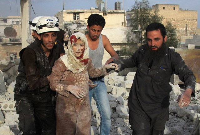 Syrian rescue workers and residents help an injured woman following a reported air strike by government forces on the rebel-held neighbourhood of Haydariya in the northern city of Aleppo on April 10, 2016. (Photo by Thaer Mohammed/AFP Photo)