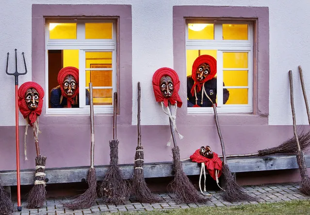 In this photo taken Saturday, February 25, 2017 witches of the Waldkircher Kandelhexen witches' club look out of windows as they prepare for celebrating the traditional witches' sabbath at the market square of Waldkirch, southern Germany, Saturday, Feb. 25, 2017. The members of the Krakeelia carnival club celebrate their annual witches' sabbath, which takes place on the Saturday before Rose Monday. (Photo by Michael Probst/AP Photo)